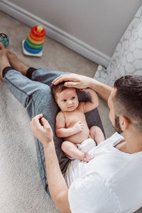 Full length of father holding baby girl while sitting at home