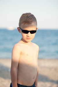 Portrait of boy wearing sunglasses standing at beach
