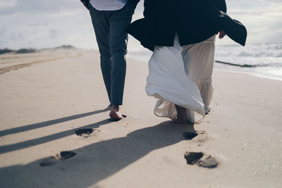 Low section of couple walking on beach