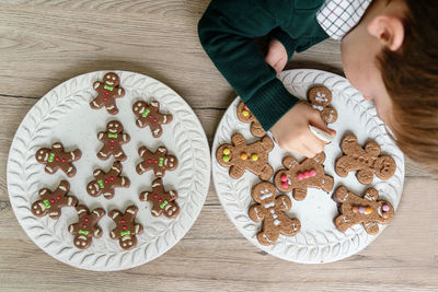 Cute boy decorating gingerbread cookies at home