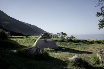 Tent on field by sea against clear sky