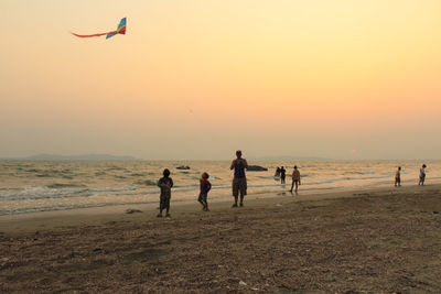 People playing on beach against clear sky