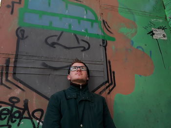 Young man standing against graffiti wall