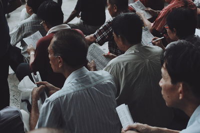 People holding papers while sitting outdoors