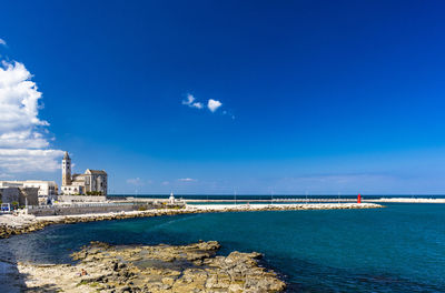 Scenic view of sea by buildings against blue sky