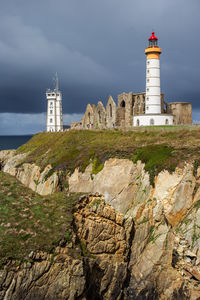 Lighthouse by sea against sky