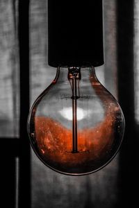 Close-up of electric lamp hanging against black background