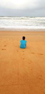 Rear view of boy sitting at beach