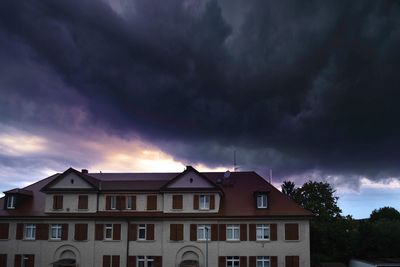 Low angle view of residential building against dramatic sky