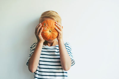 Full length of a girl covering face against white background