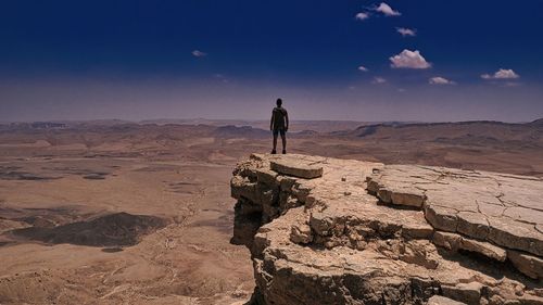 Man standing on cliff against sky