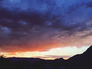Scenic view of mountains against cloudy sky at sunset
