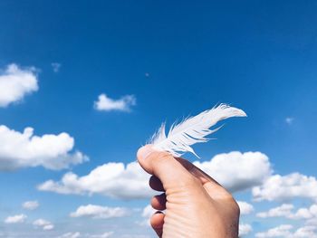 Close-up of hand holding umbrella against sky