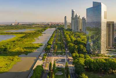 Aerial view of river with trees and buildings in city against sky