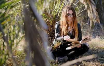 Close-up of teenager reading book while sitting on field