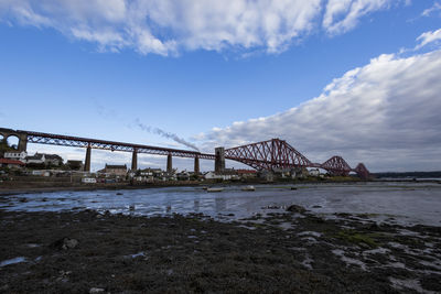 Bridge over river against cloudy sky