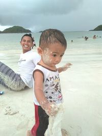 Rear view of father and son on beach against sky