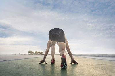 Low angle view of man taking running stance against sky