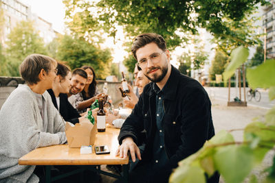 Portrait of smiling young male sitting with friends and enjoying at social gathering
