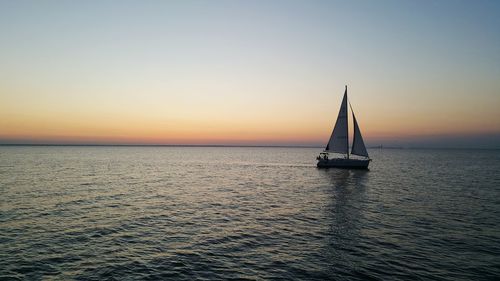 Boat sailing in sea at sunset