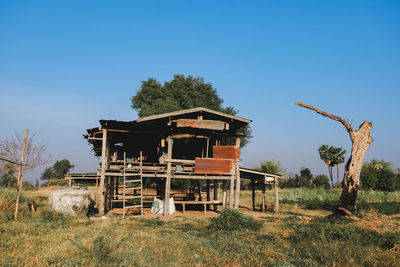 Abandoned house on field against clear blue sky