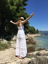 Full length of woman standing by tree against clear sky