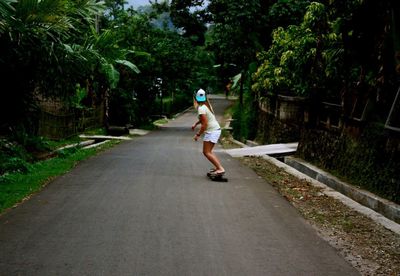 Full length of woman skateboarding on road