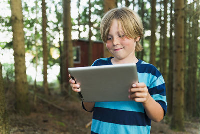 Boy using digital tablet in forest