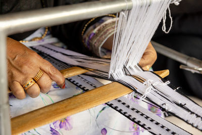 Closeup on hands of an old emirati woman using traditional weaving machine