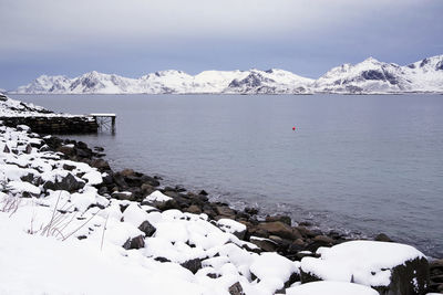 Scenic view of sea by snowcapped mountains against sky