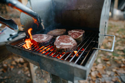 Cropped image of man preparing food on barbecue grill in yard