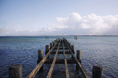 Broken pier over sea against sky