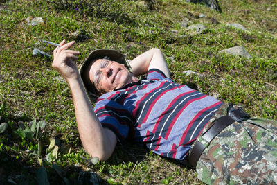 Man holding cigarette while lying on grass 