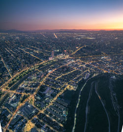 Aerial view of illuminated cityscape against sky during sunset