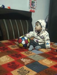 Cute boy sitting on bed at home