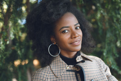 Beautiful african american young woman with afro hairstyle and large hoop earrings in a stylish coat 