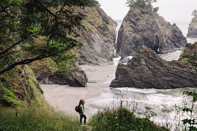 Woman standing with a view to a secret beach in oregon coast. 