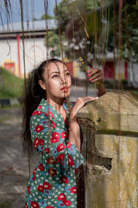 Portrait of young woman standing against wall