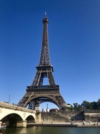 Eiffel tower and bridge against blue sky in paris