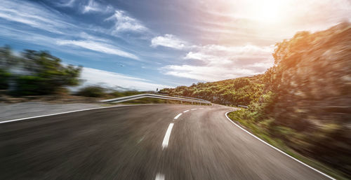 Blurred motion of road amidst land against sky