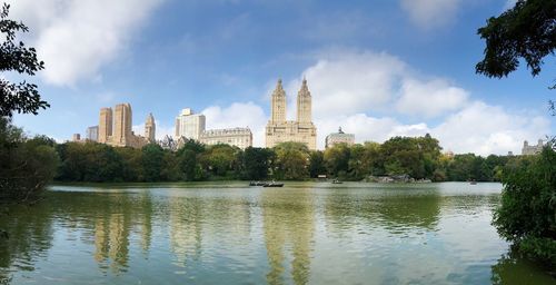View of buildings by river against cloudy sky