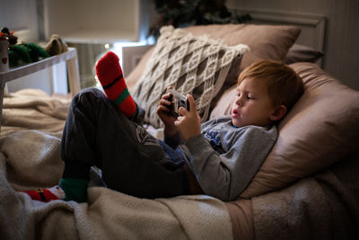 High angle view of boy playing game in mobile phone