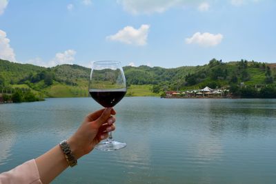 Man drinking glass in water against sky