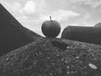 Low angle view of an apple on rock against sky