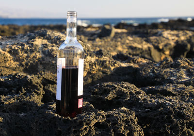 Close-up of bottle on rock at beach