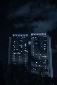 Low angle view of illuminated buildings against sky at night