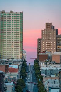 Modern buildings in city against sky during sunset