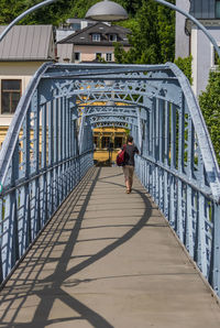 Rear view of man walking on footbridge