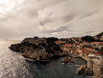 Buildings by sea against sky