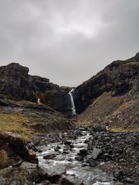 Low angle view of person standing on mountain against sky